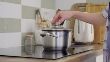 Sıcak su dolu tava ve dokunmatik tabağı kapatan eller.