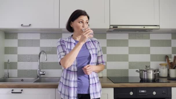 Reife Frau mit einem Glas Wasser in der Küche — Stockvideo