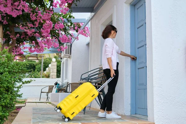 Al aire libre, viajera mujer con maleta amarilla abriendo la puerta de cierre de la casa — Foto de Stock