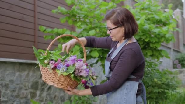 Женщина садовник, флорист в саду с корзиной свежих сорванных садовых весенних цветов — стоковое видео