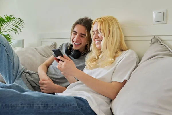 Feliz rindo hipster adolescentes masculino e feminino se divertindo usando o smartphone juntos — Fotografia de Stock