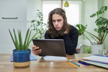 Çevrimiçi ders, erkek öğrenci evde dijital tablet kullanarak çalışıyor.