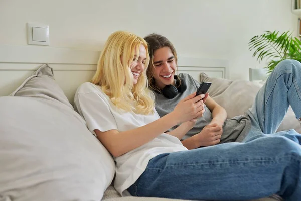 Feliz rindo hipster adolescentes masculino e feminino se divertindo usando o smartphone juntos — Fotografia de Stock