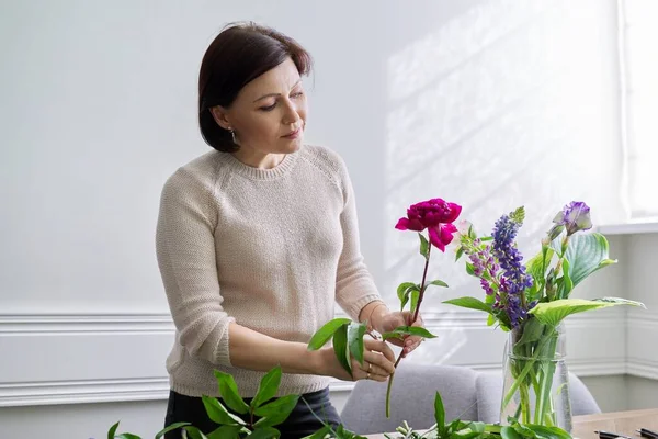 Volwassen vrouw thuis met lente bloemen — Stockfoto