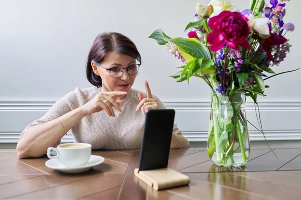 Sonriente mujer de mediana edad hablando mirando la pantalla del teléfono inteligente — Foto de Stock