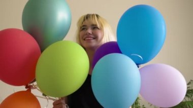 Renkli balonları yakın ve mutlu gülümseyen sarışın genç bayan yüzleri