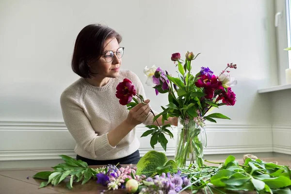 Volwassen vrouw thuis met lente bloemen — Stockfoto