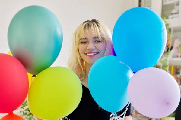 Close-up van gekleurde ballonnen en gelukkig glimlachen gezicht van blond tiener vrouw — Stockfoto