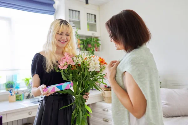 Mamma gratulerar dotter med bukett blommor och överraskning presentförpackning — Stockfoto