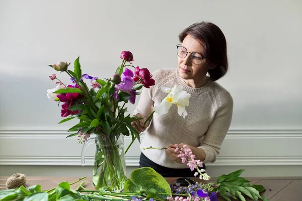 Volwassen vrouw thuis met lente bloemen — Stockfoto