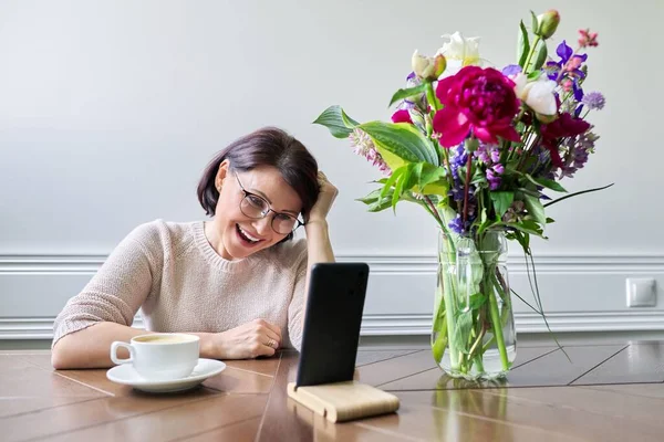 Souriant femme d'âge moyen parlant en regardant l'écran du smartphone — Photo