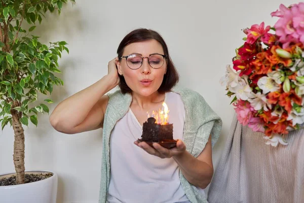 Зріла красива жінка з маленьким тортом на день народження з палаючими свічками — стокове фото