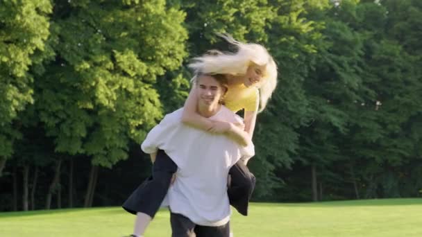 Bir çift genç erkek ve kız 16-17 yaşları yeşil çimlerin üzerinde parkta eğleniyorlar. — Stok video