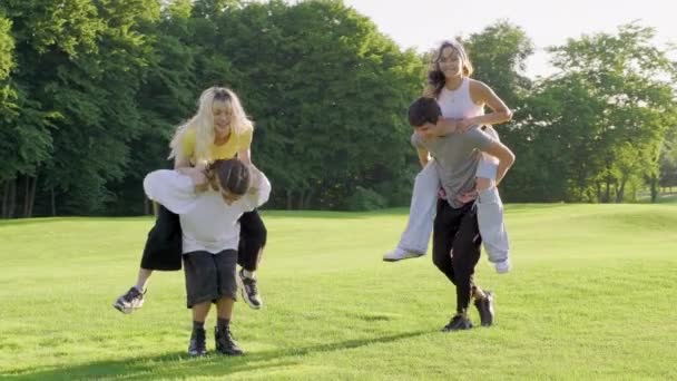 Tinédzserek csoportja 16, 17 évesek szórakoznak együtt nyáron a parkban a zöld gyepen — Stock videók