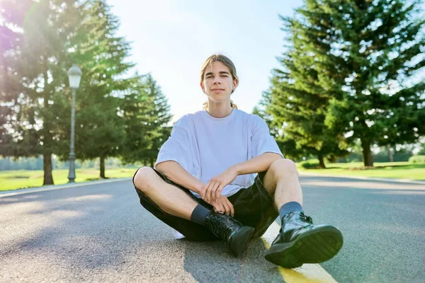 Fashion portret van hipster tiener guy zitten op de weg. — Stockfoto