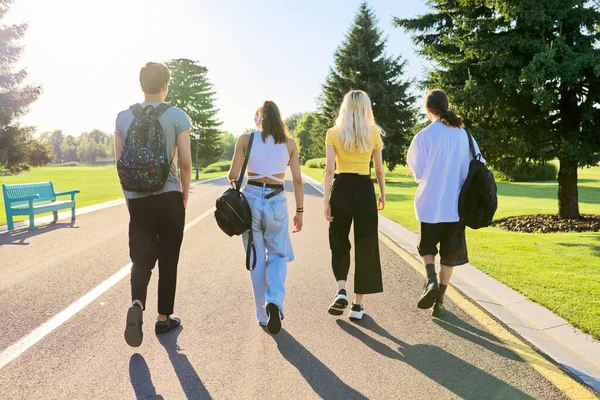 Grupa nastoletnich przyjaciół w słoneczny letni dzień spacerująca razem po drodze, widok z tyłu — Zdjęcie stockowe