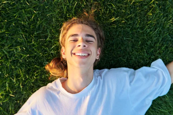 Close-up gezicht van knappe jongen 16, 17 jaar oud op groen gras, top uitzicht — Stockfoto