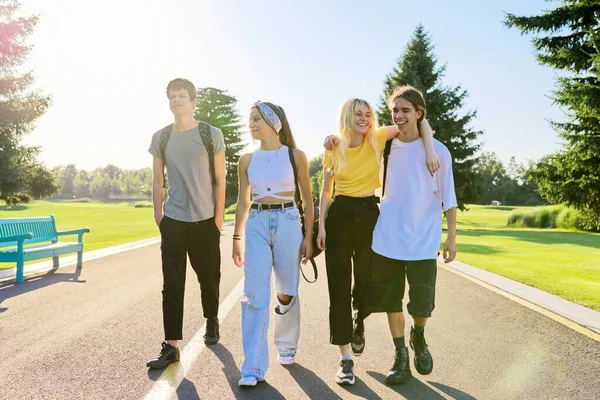 En plein air, quatre adolescents marchent ensemble sur la route — Photo