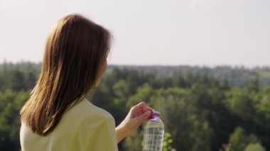 Sıcak yaz gününde şişeden su içen kadın