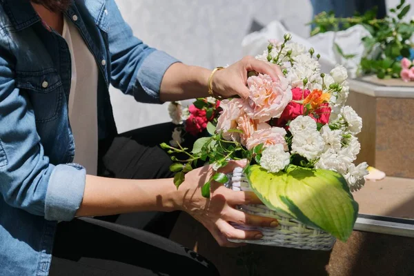 女性花屋は屋外で花の配置を行います。フラワーバスケット作成ワークフロー — ストック写真