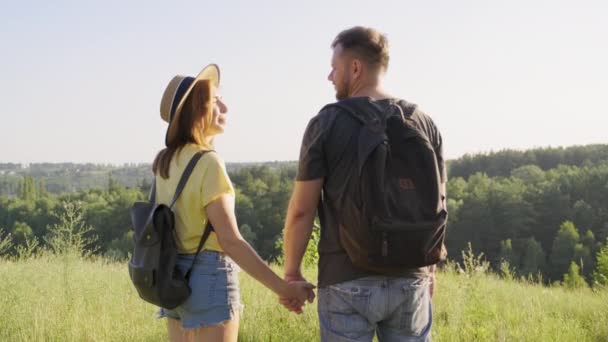 Feliz casal meia-idade de mãos dadas, homem e mulher com mochilas, visão traseira — Vídeo de Stock