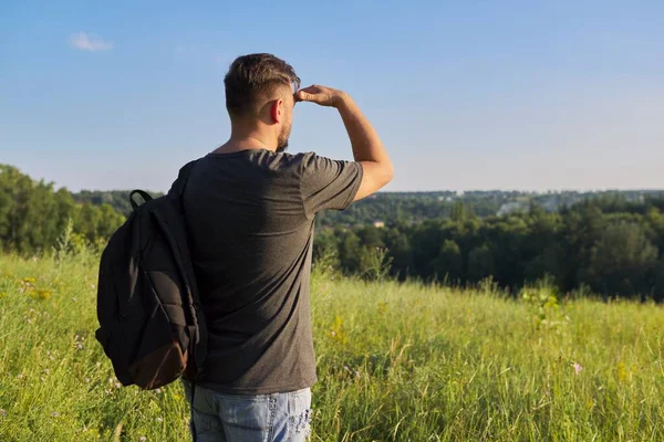 Back view of middle-aged man with backpack looking in distance at natural hills — Stock Photo, Image