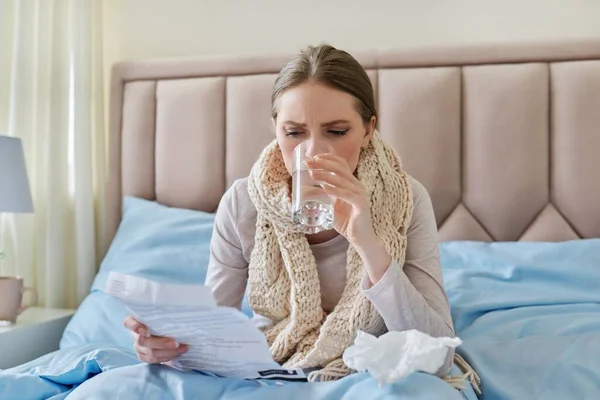 Jeune femme malade à la maison au lit, instructions de lecture féminines pour les médicaments — Photo