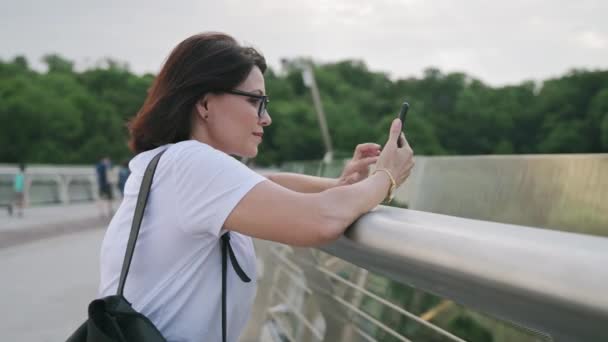 Bella femmina 40 anni in occhiali guardando lo schermo del telefono — Video Stock