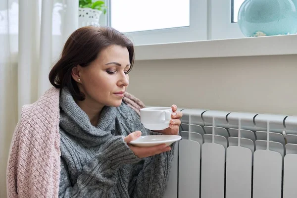 Temporada de invierno, mujer calentándose cerca del radiador de calefacción doméstica — Foto de Stock