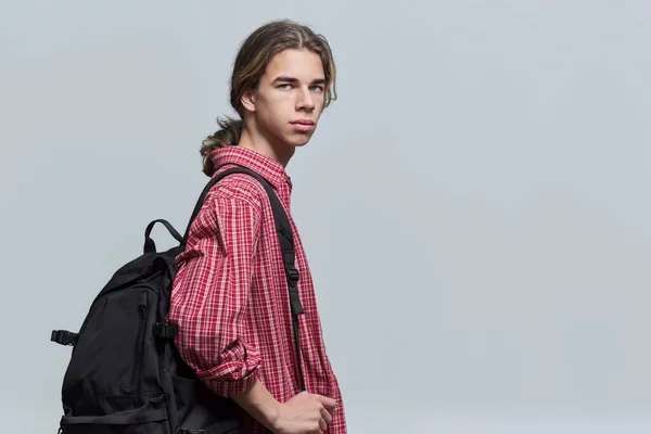 Guy student teenager with backpack looking at camera on light background — Stockfoto