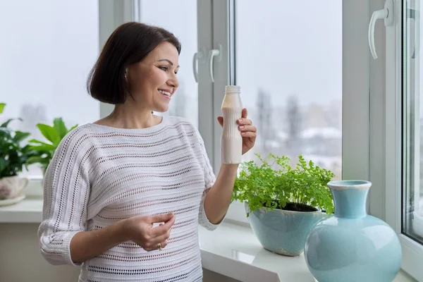 Frau mittleren Alters trinkt Milchprodukte, Joghurt, Milch in der Flasche — Stockfoto