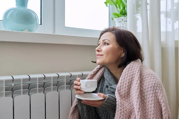 Temporada de invierno, mujer calentándose cerca del radiador de calefacción doméstica — Foto de Stock