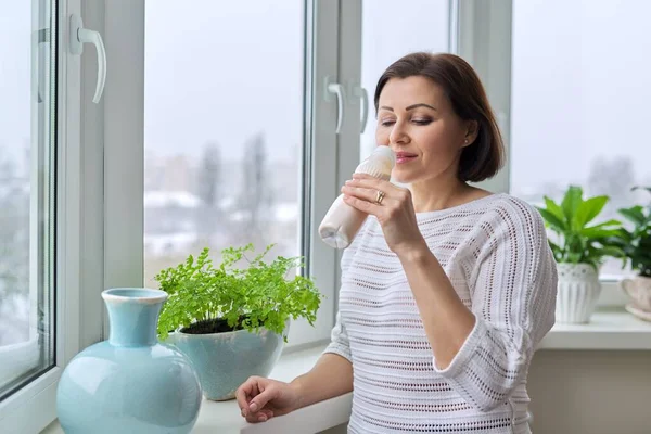 Medelålders kvinna som dricker mjölkprodukter, yoghurt, mjölk i flaska — Stockfoto