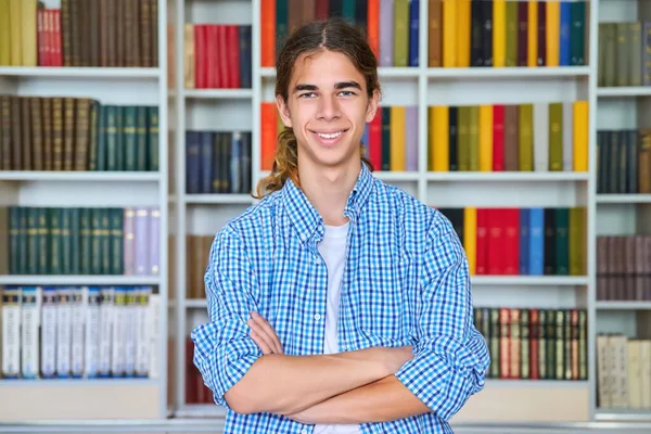 Solo retrato de sonriente confiado estudiante adolescente mirando a la cámara en la biblioteca —  Fotos de Stock