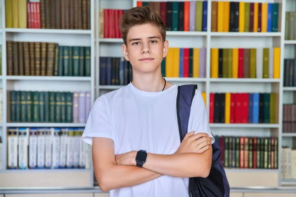 Single portret van ernstige zelfverzekerde mannelijke student tiener op zoek naar camera in de bibliotheek — Stockfoto