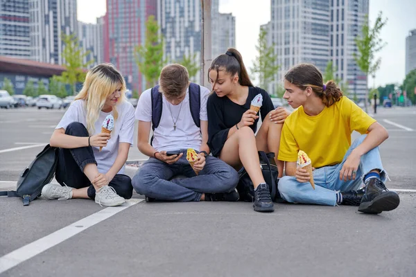 Group of teenagers with ice cream looking together at smartphone, urban style — Stock Photo, Image