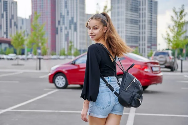 Модна красива усміхнена дівчина-підліток в шортах з рюкзаком дивиться на камеру — стокове фото