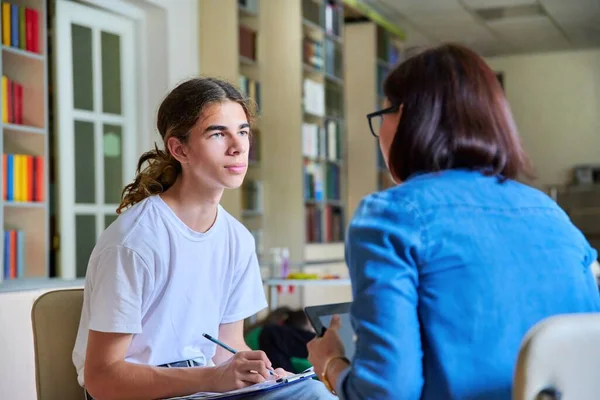 Kobieta szkoła psycholog nauczyciel mówi i pomaga student, mężczyzna nastolatek — Zdjęcie stockowe