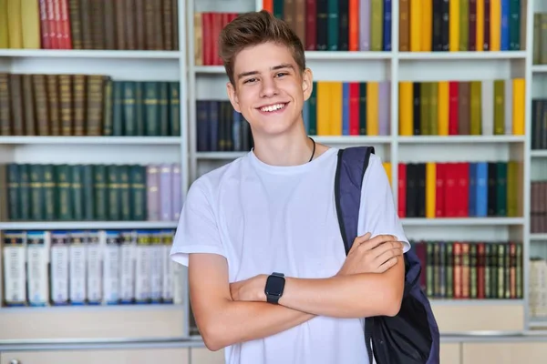 Jediný portrét usmívajícího se sebevědomého studentského teenagera dívajícího se do kamery v knihovně — Stock fotografie