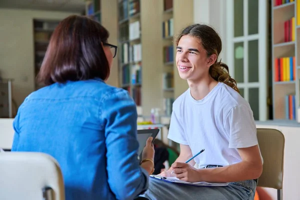 Kobieta szkoła psycholog nauczyciel mówi i pomaga student, mężczyzna nastolatek — Zdjęcie stockowe