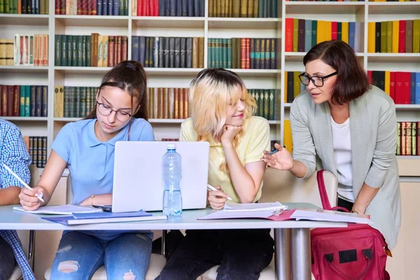 Dívky dospívající studenti studující v knihovně s učitelem mentor — Stock fotografie