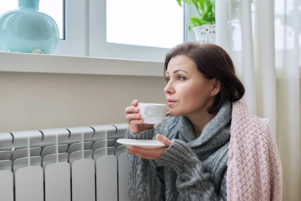 Temporada de invierno, mujer calentándose cerca del radiador de calefacción doméstica —  Fotos de Stock
