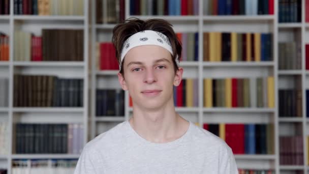 Solo retrato de sonriente confiado estudiante adolescente mirando a la cámara en la biblioteca — Vídeo de stock