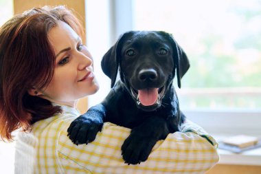Orta yaşlı kadın ve siyah labrador köpek yavrusu portresi