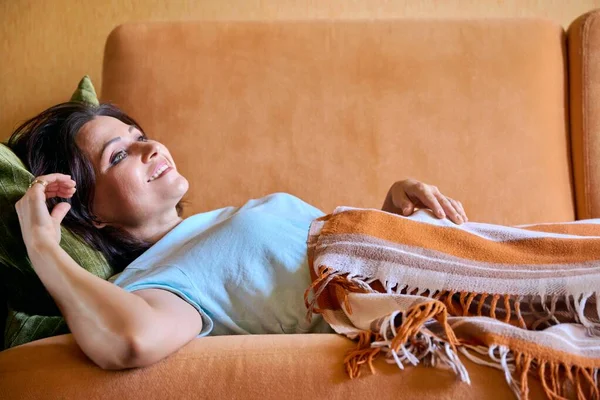 Feliz mujer de mediana edad tumbada en el sofá en casa —  Fotos de Stock