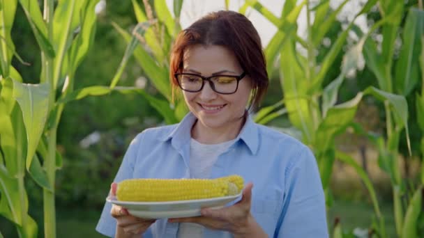 Mujer de mediana edad con maíz hervido en plato — Vídeos de Stock