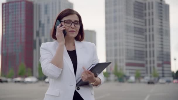 Серьезный среднего возраста уверенная деловая женщина разговаривает на смартфоне — стоковое видео