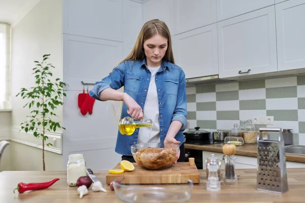 Молода жінка готує курку на відпочинок, маринуючи зі спеціями оливковою олією, вдома на кухні — стокове фото