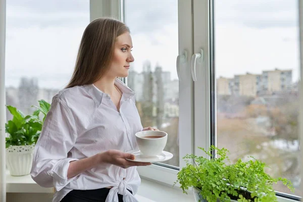 Retrato de mujer joven con taza de café cerca de la ventana de otoño de invierno — Foto de Stock