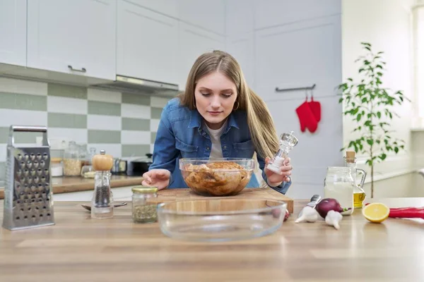 Молода жінка на домашній кухні готує м'ясо, курка — стокове фото